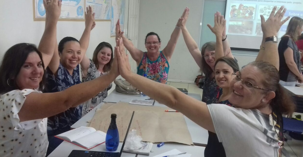 Docentes de la red con las manos unidas en alto durante una sesión de trabajo