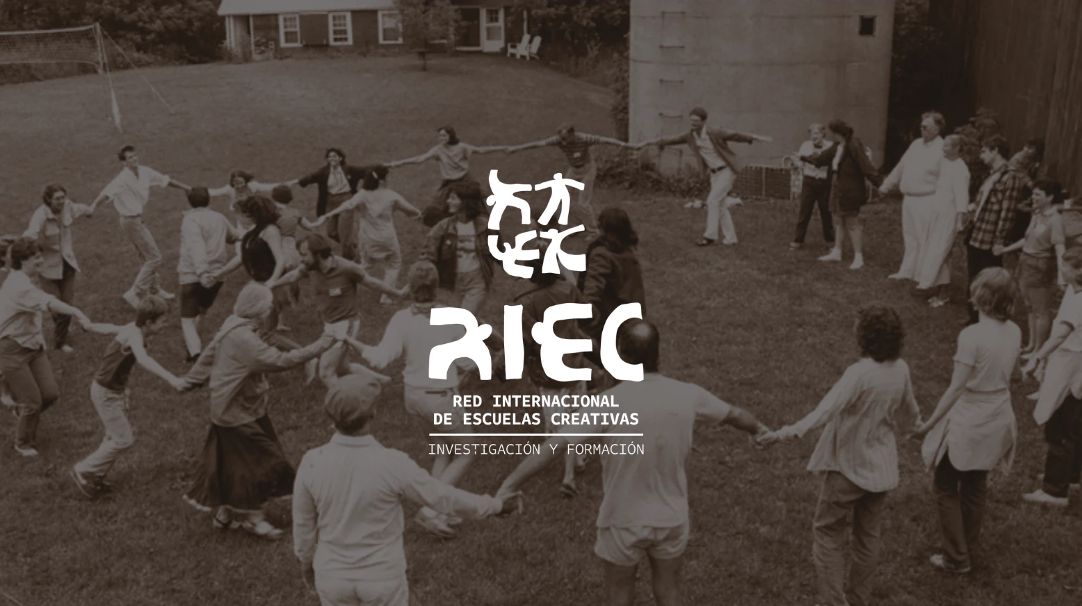 Gran corro de personas cogidas de la mano en un jardín, con el logotipo de la Red Internacional de Escuelas Creativas al centro
